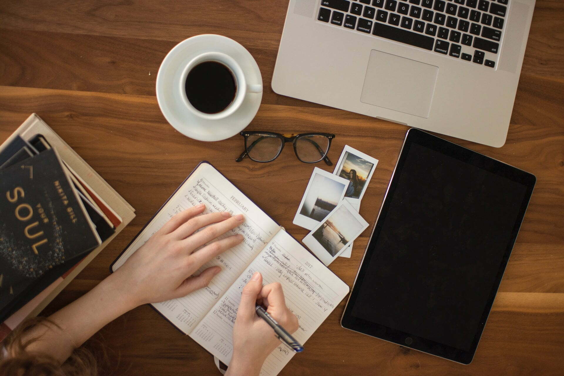 a person holding a tablet and a cup of coffee on a table