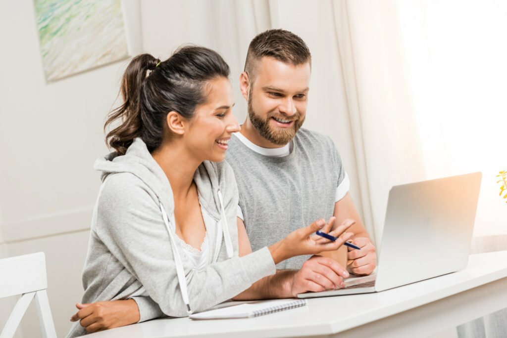 portrait of smiling couple discussing project while working at home together